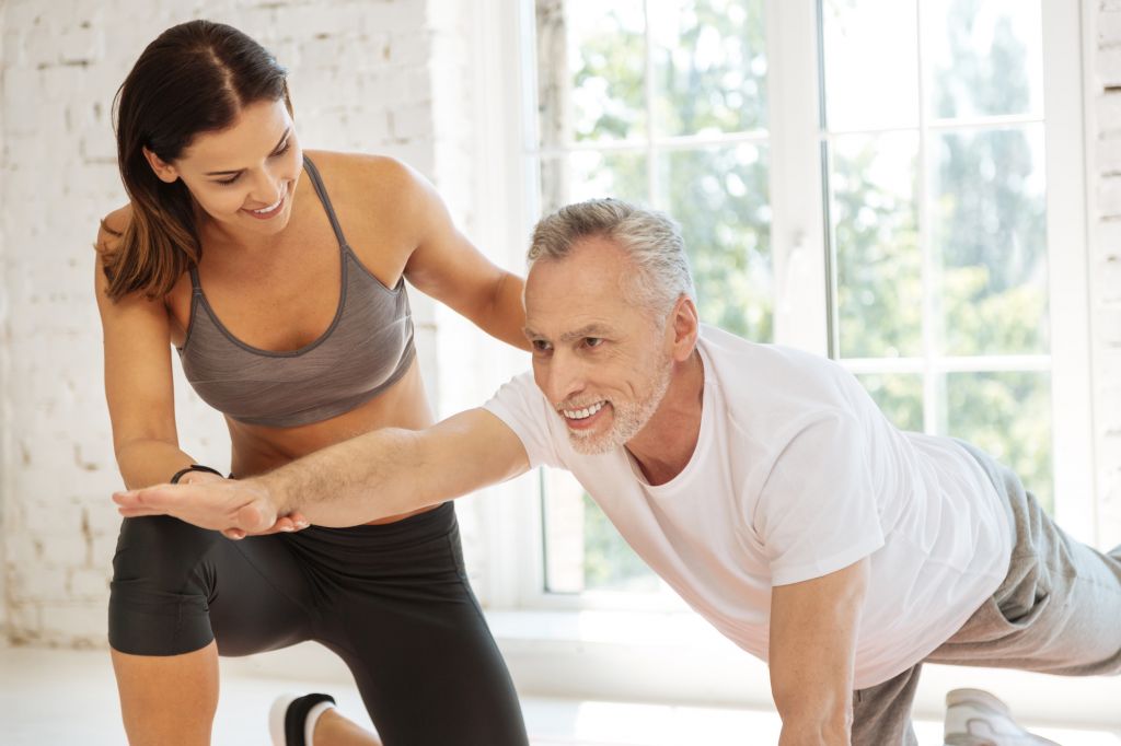 Good support. Delighted mature bearded male person expressing positivity while doing exercises and raising right arm