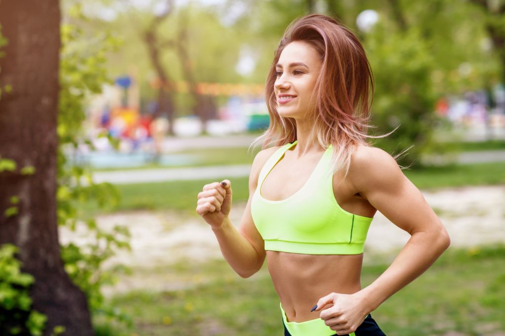 Beautiful young woman running in the green park.